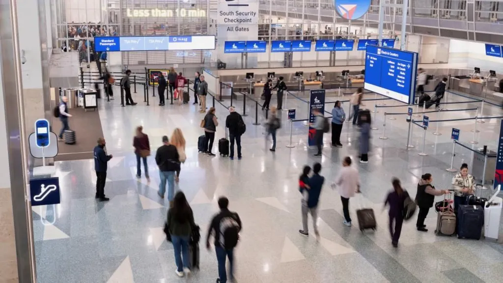 Travellers seen from above walk through the departures and check in area of an airport. 