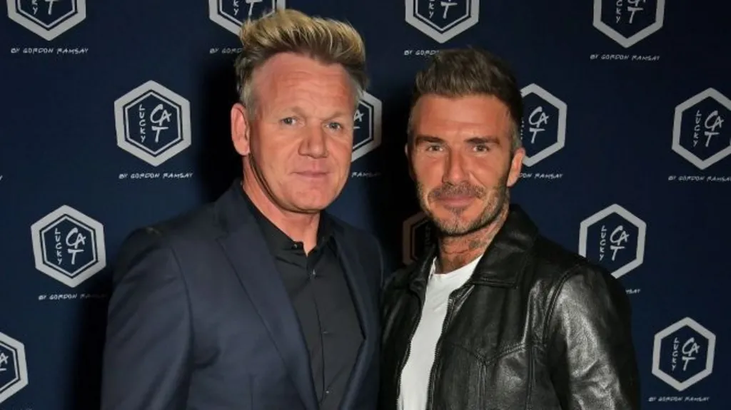 Gordon Ramsey in a navy blue suit and black shirt, with David Beckham in a black leader jacket and white t-shirt.
