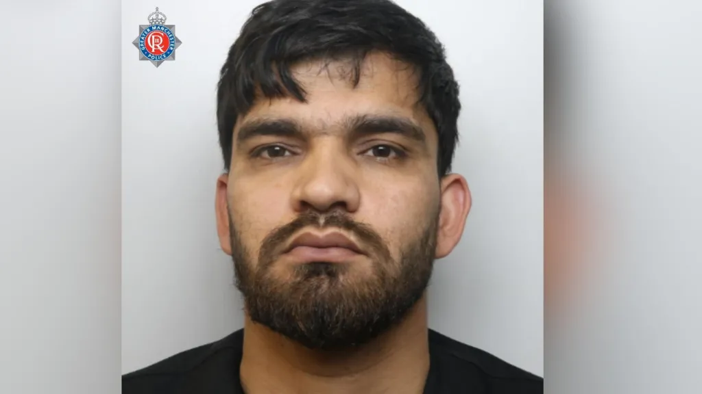 Man with short hair and black beard in police mugshot.