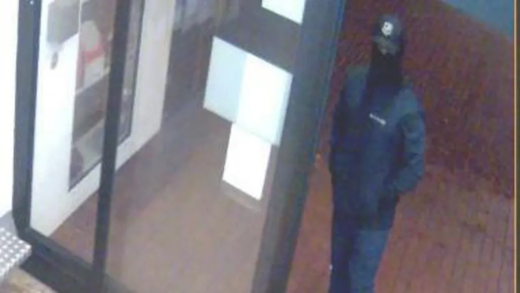 A man with his hands in his pockets in a mask