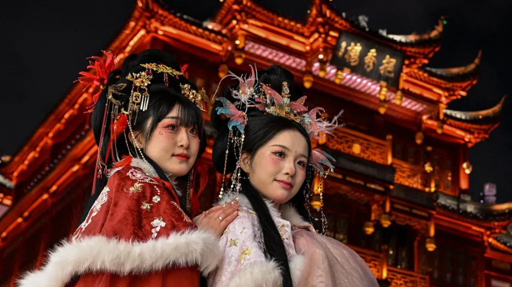Women wearing traditional costumes pose for photographs in front of a Chinese temple