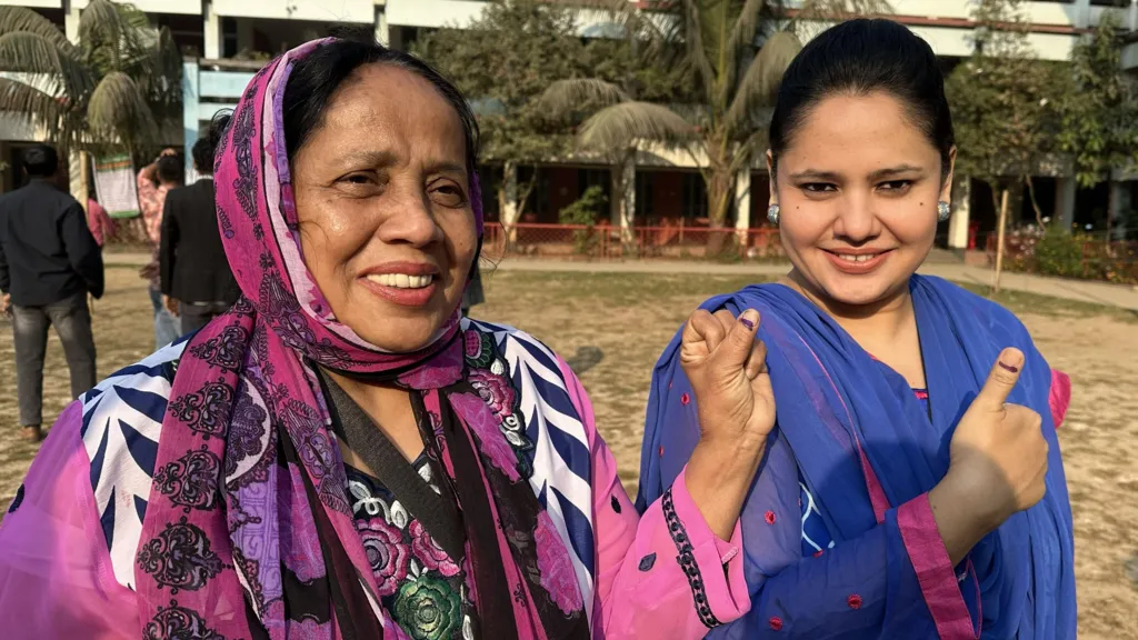 A mother and daughter smile on voting day. The daughter gives a thumbs up sign