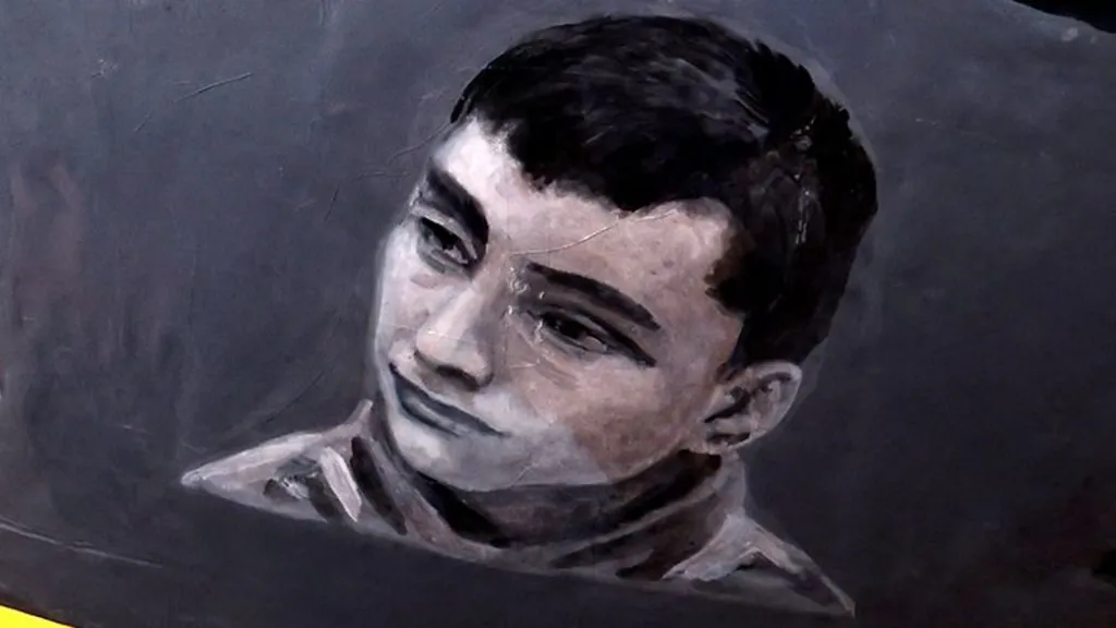 Close up of the helmet featuring a black and white image of Dmytro Sarpar, who has dark hair and thick eyebrows.