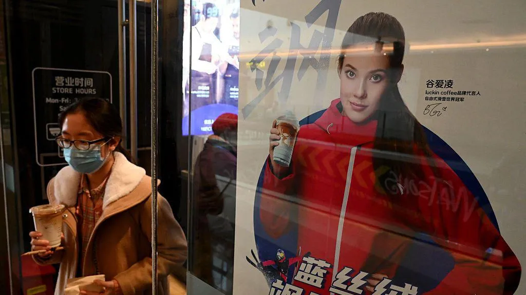 A woman walk past a poster showing China's US-born gold medallist Eileen Gu