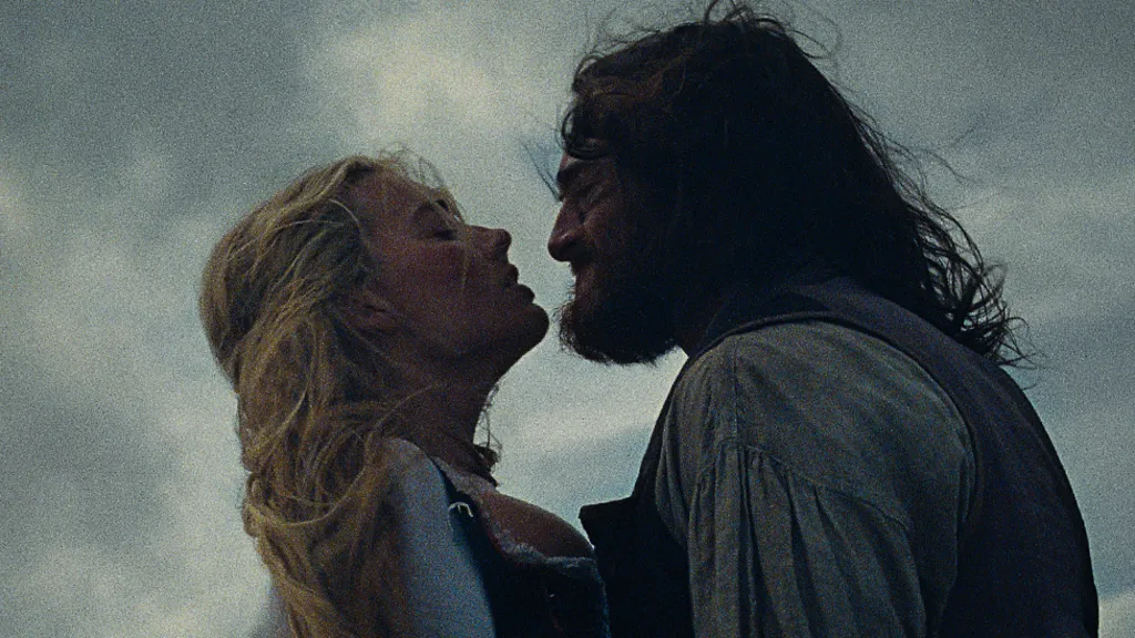 Character Cathy and Heathcliff, both with windswept hair and in period costume, share a passionate embrace set against a moody sky